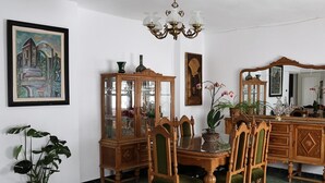 A dining room with a wooden table, chairs, a cabinet, and a chandelier.