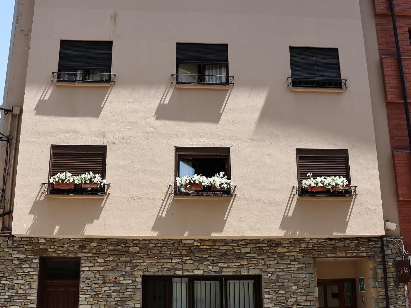 A building with a stone facade, multiple windows with shutters, and flower boxes on the balconies.