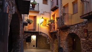A narrow alleyway with stone walls and balconies, illuminated by warm lighting.