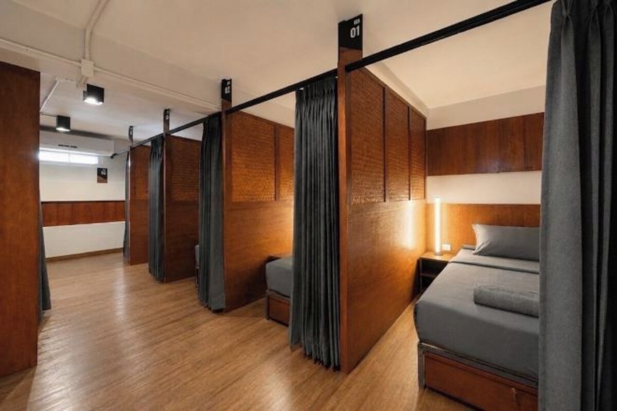 A hotel room with a bed, a nightstand, a lamp, and a curtain.