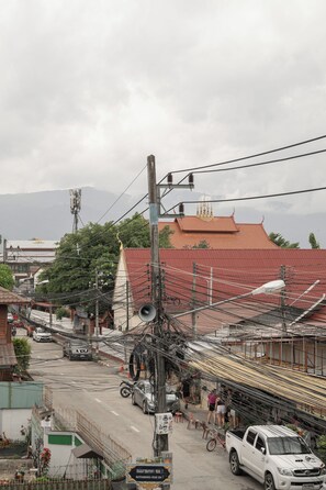 A street view with a red-roofed building, a white pickup truck, and a bicycle. - Ed Hostel Rachamakka (Chiang Mai)