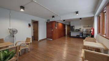 A spacious room with wooden flooring, a kitchenette area, and a seating area with chairs and a table.