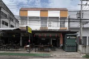 A building with a ground-level restaurant and a green structure labeled "EXCHANGE" on the right. - Ed Hostel Rachamakka (Chiang Mai)