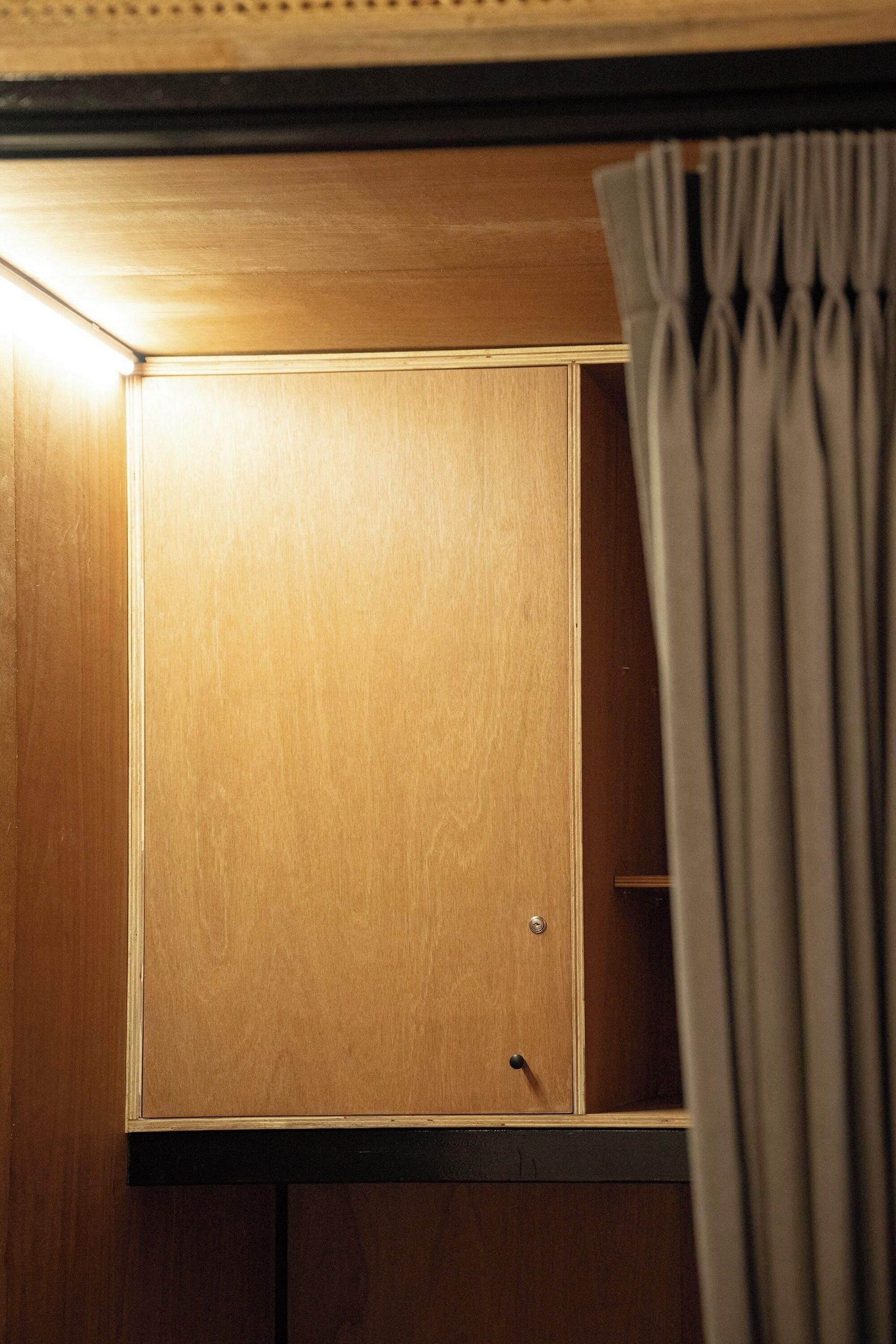 A wooden cabinet with a single visible drawer, a small circular handle, and a metal lock.