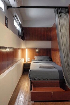 A compact bedroom with a bed, bedside table, and a nightstand. - Ed Hostel Rachamakka (Chiang Mai)