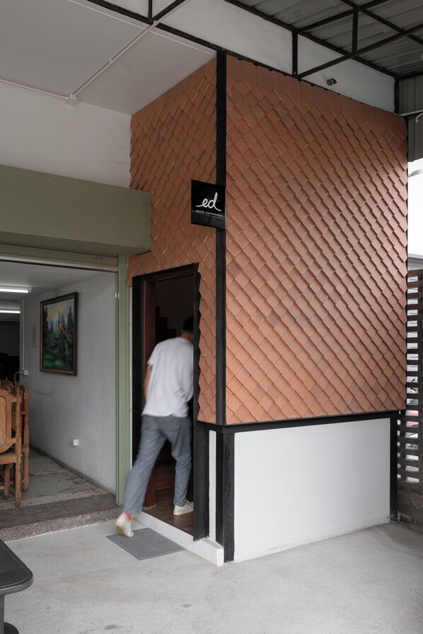 A person entering a room with a distinctive textured wall and a sign above the door. - Ed Hostel Rachamakka (Chiang Mai)