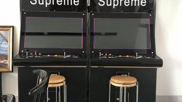 Dos máquinas de arcade llamadas 'Supreme' con paneles de control y taburetes.