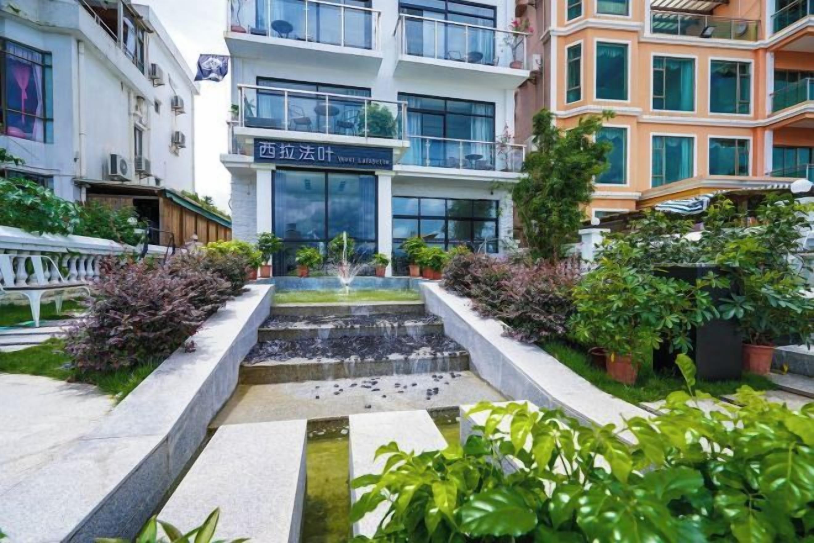 Un patio con fuente de agua, plantas en macetas y un edificio con señalización.