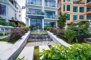 A courtyard with a water feature, potted plants, and a building with signage. - West Lafayette seaview Inn (Shenzhen)