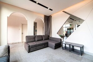A modern living room with a sectional sofa, a bench, and a staircase. - West Lafayette seaview Inn (Shenzhen)