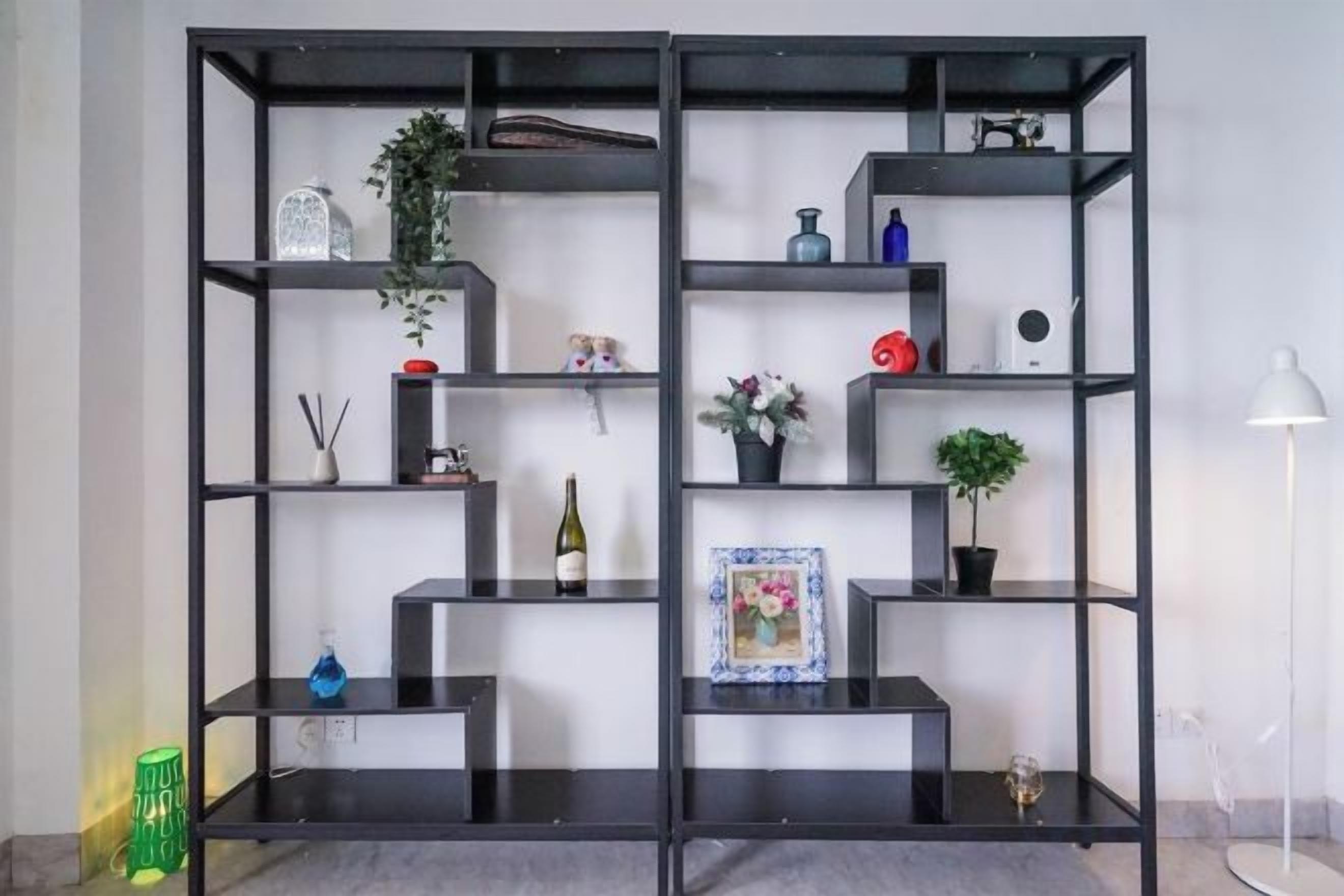 Una estantería negra con varios objetos decorativos y una lámpara de pie.