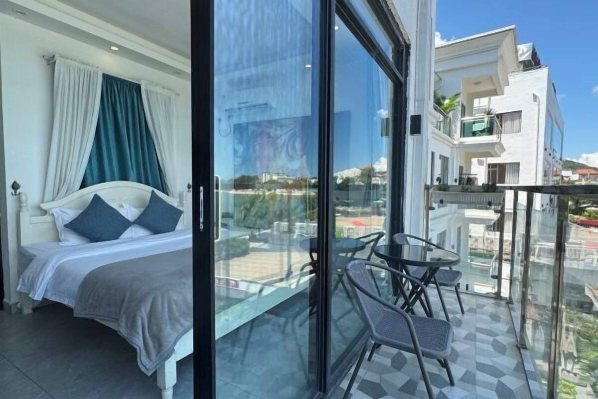 Un dormitorio con cama, puerta de cristal que da a un balcón con sillas y una mesa.