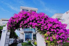 A hotel entrance with a white facade, a clear sky, and a sign above the entrance. - West Lafayette seaview Inn (Shenzhen)