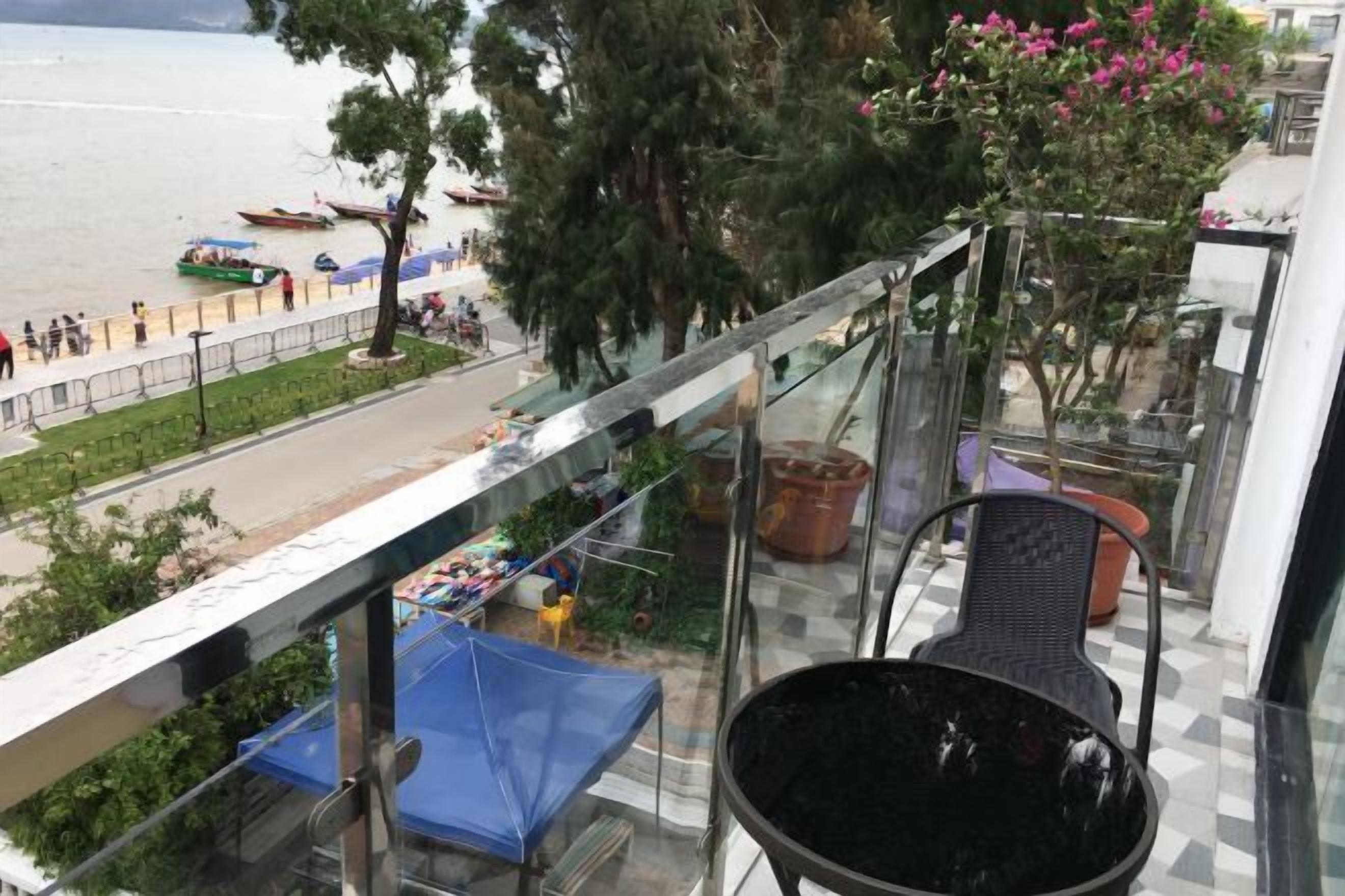 Un balcón con vista al mar, una mesa, sillas y plantas en macetas.