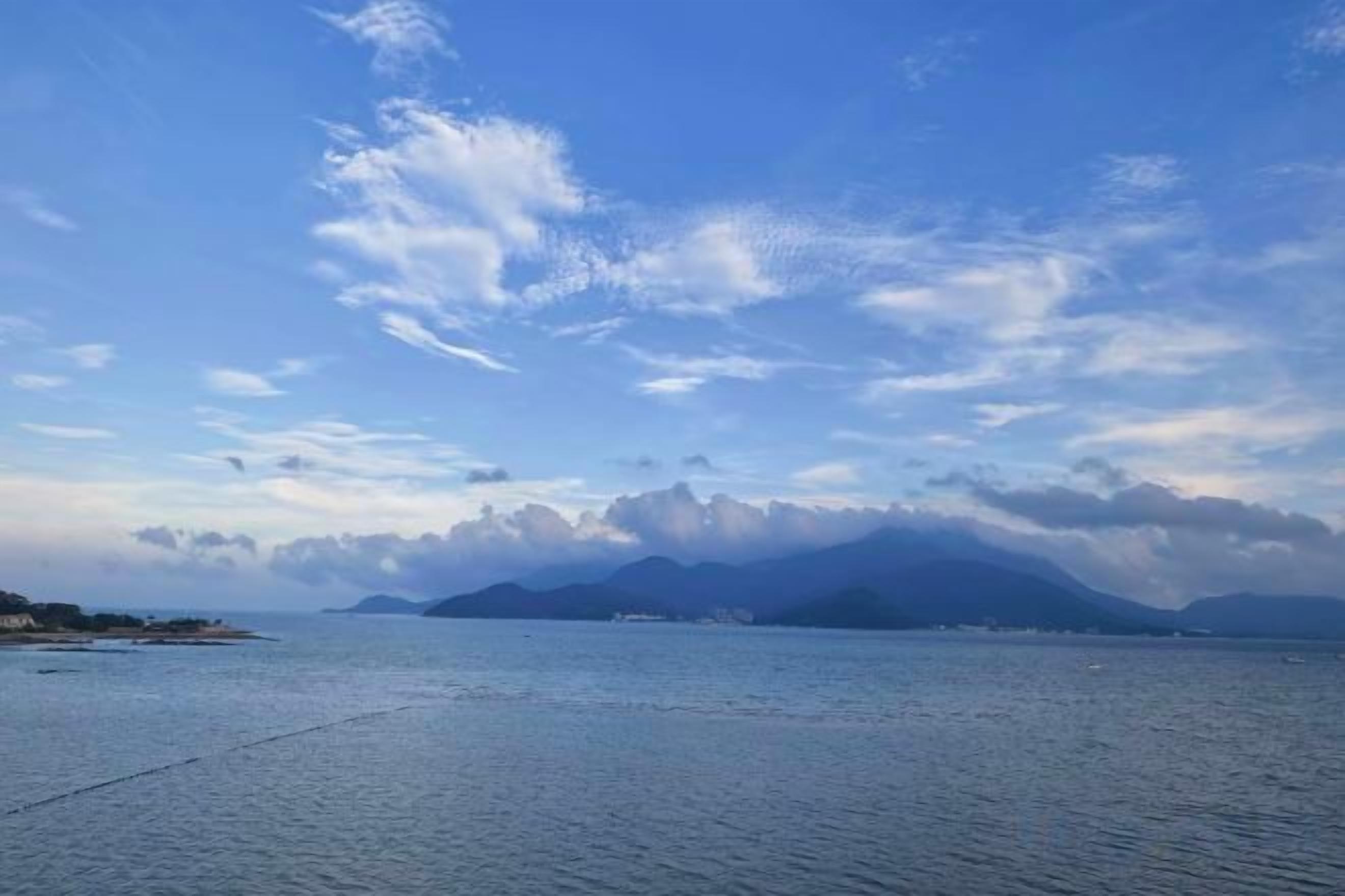 A calm body of water with a distant mountain range and a clear sky.