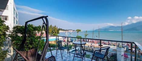 Un balcon avec vue sur la mer, aménagé avec des chaises et des tables.