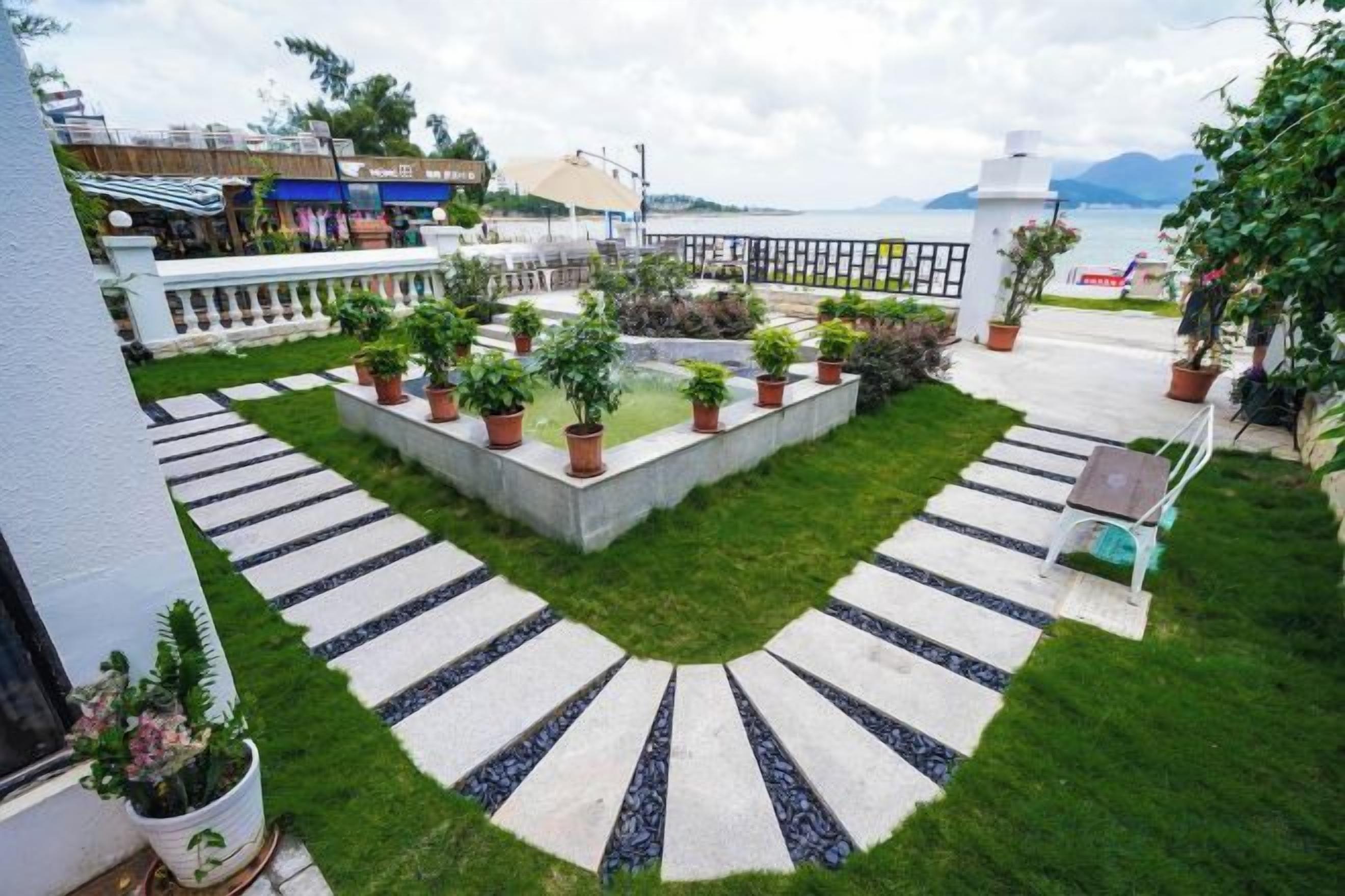 A courtyard with a central garden, seating area, and a view of the sea.