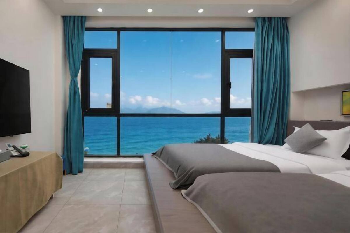 Habitación de hotel con un ventanal grande, una cama, televisión y escritorio.