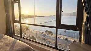 A room with a large window overlooking a body of water, a bed, and a table. - West Lafayette seaview Inn (Shenzhen)