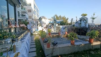 Un jardín en la azotea con plantas en macetas y una mesa con objetos.