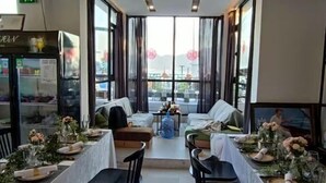 A dining area with tables set for a meal, a sofa, and a large window with curtains. - West Lafayette seaview Inn (Shenzhen)