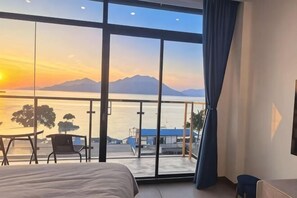 A bedroom with a large window, a bed, and a view of a body of water and mountains. - West Lafayette seaview Inn (Shenzhen)