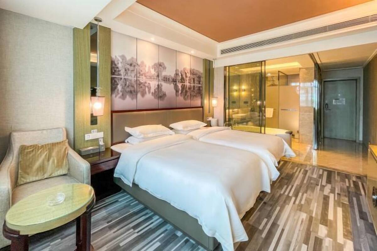 Une chambre d’hôtel avec un grand lit, une chaise, une petite table et un tableau au mur.