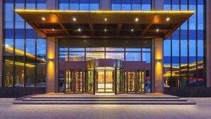 A modern hotel entrance with a revolving door, large windows, and a covered entrance area.
