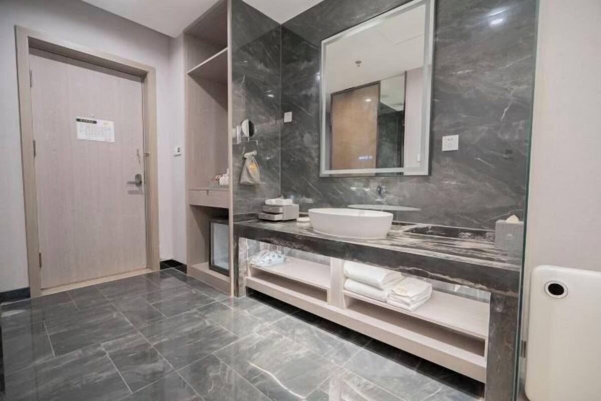 Casa de banho moderna com toucador de mármore, espelho grande e porta com placa.