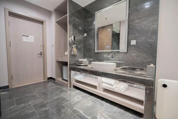 Casa de banho moderna com toucador de mármore, espelho grande e porta com placa.