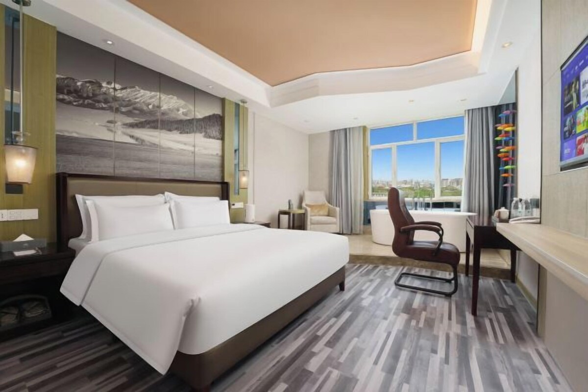 Une chambre d’hôtel avec un grand lit, un bureau et une vue sur l’extérieur.