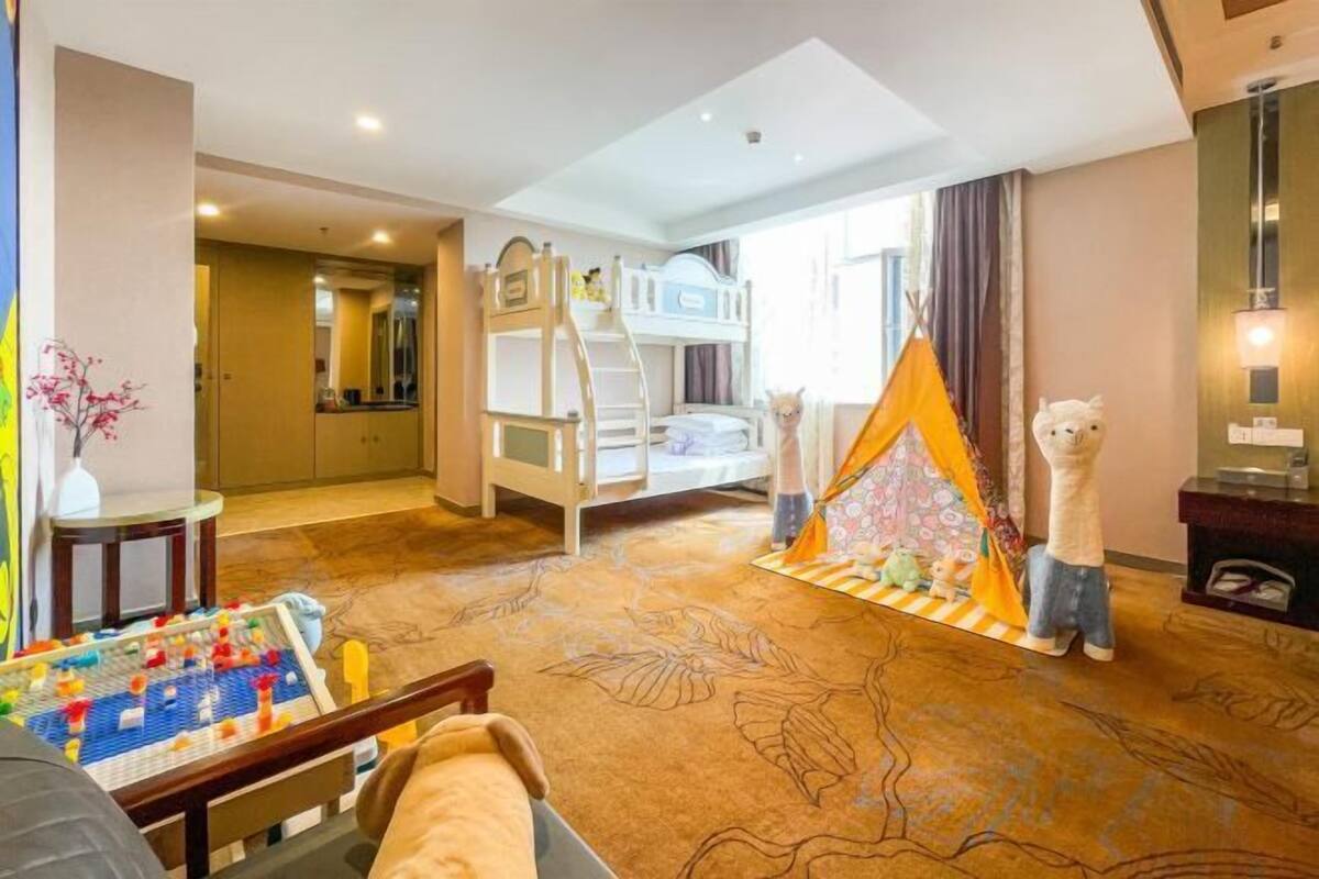 Un espace de jeux pour enfants avec des lits superposés, une tente et des peluches.