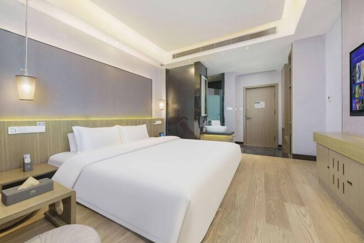 Une chambre d’hôtel moderne avec un grand lit, des tables de chevet, un miroir et un plancher en bois.