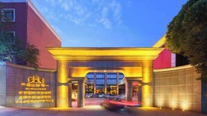A hotel entrance with a large archway, illuminated by warm lighting, and a sign with text.