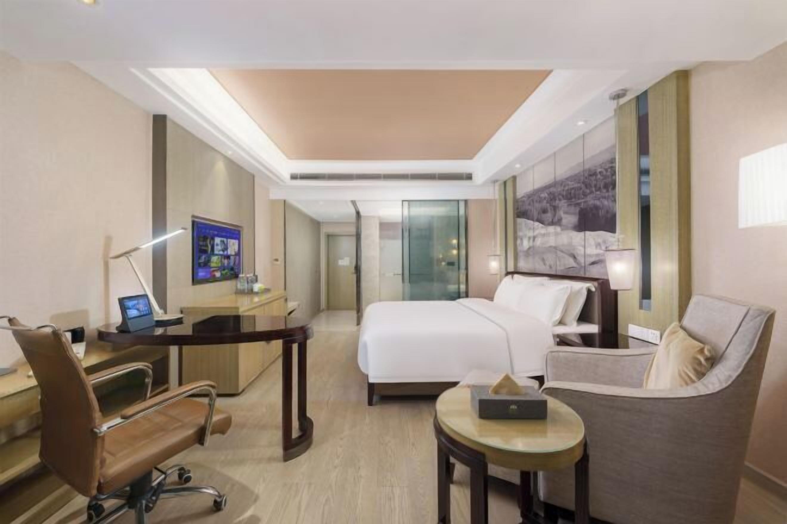 Une chambre d’hôtel avec un lit, un bureau, une chaise et une petite table.