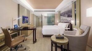 A hotel room with a bed, desk, chair, and a small table.
