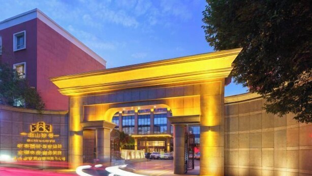 A hotel entrance with a modern design, featuring a prominent archway and illuminated signage.