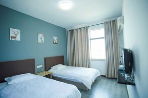 Quarto de hotel com duas camas, televisão e janela com cortinas.