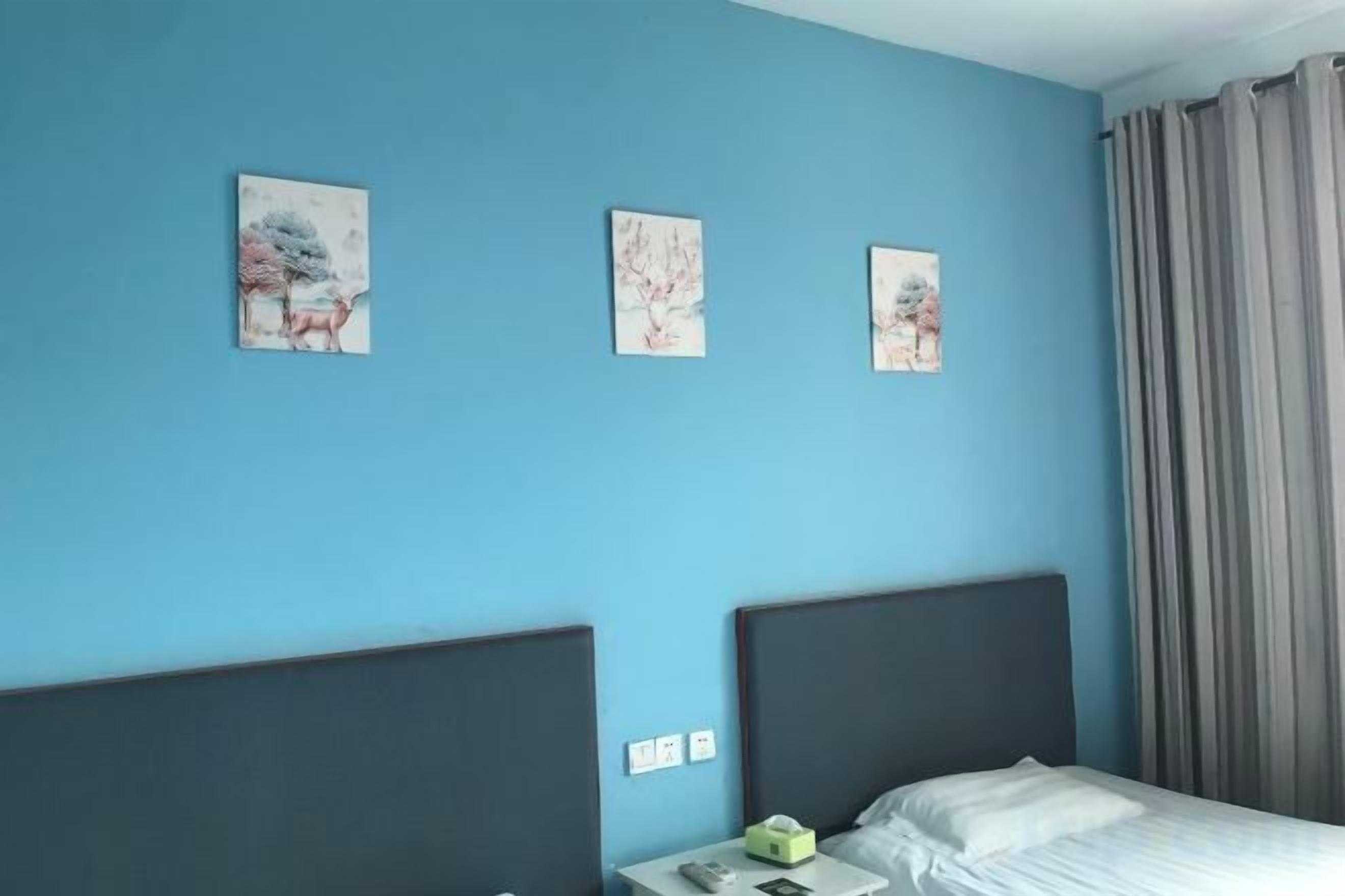 Una habitación con una cama, una mesita de noche y tres obras de arte colgadas en la pared.