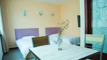 A hotel room with two beds, a small table, and a chair.