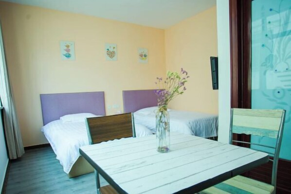 Quarto de hotel com duas camas, uma mesinha e uma cadeira.