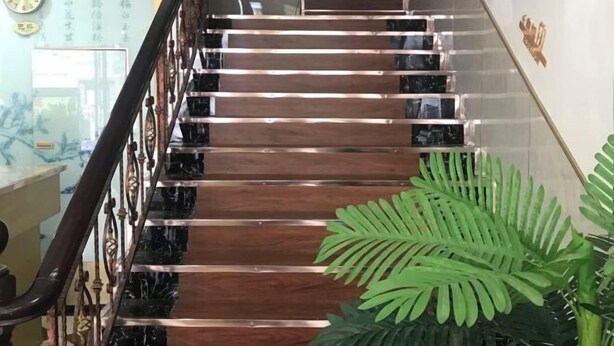 A staircase with wooden steps and a metal railing, leading to an upper floor.