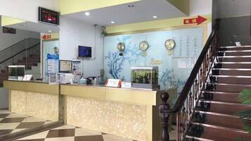 A reception desk with a digital clock, a wall-mounted clock, and a sign indicating directions.