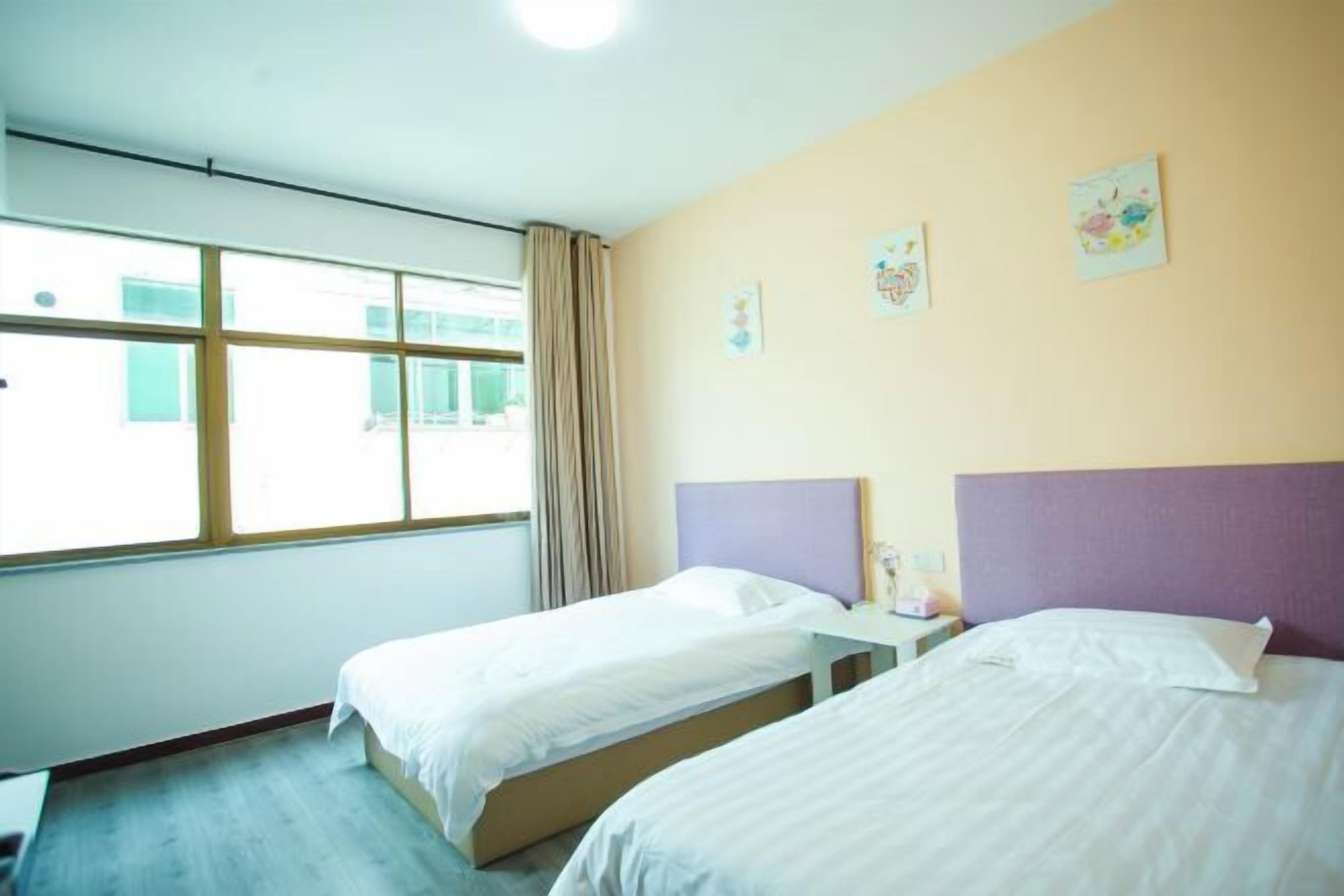 Una habitación de hotel con dos camas, una ventana con cortinas y obras de arte en la pared.