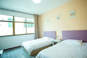 Una habitación de hotel con dos camas, una ventana con cortinas y obras de arte en la pared.