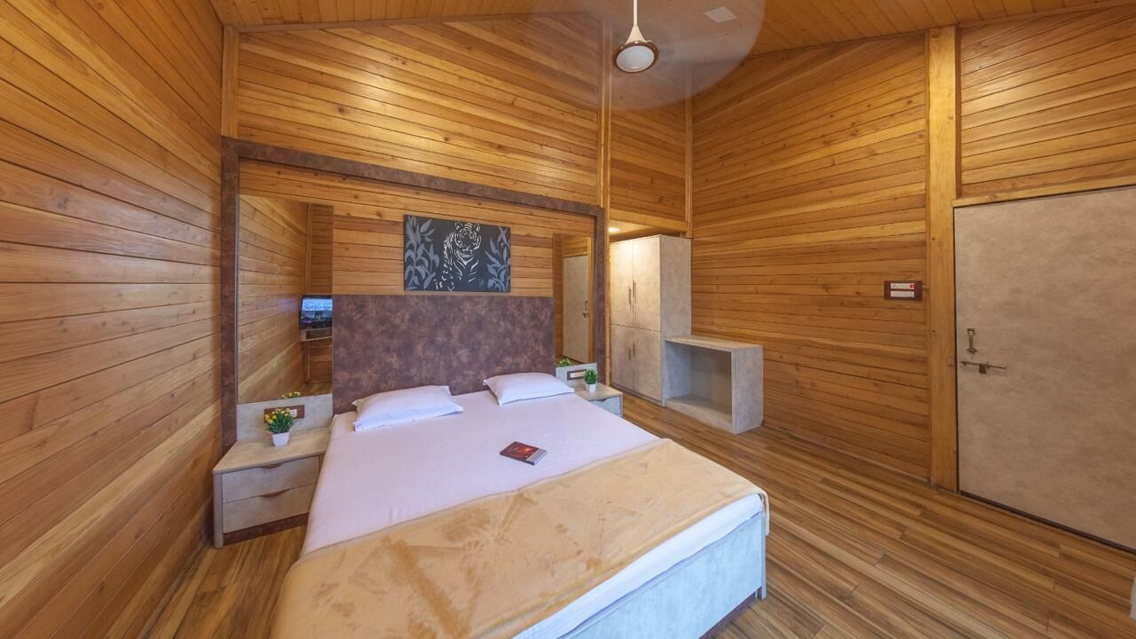A wooden-paneled bedroom with a bed, nightstands, a TV, and a wardrobe.