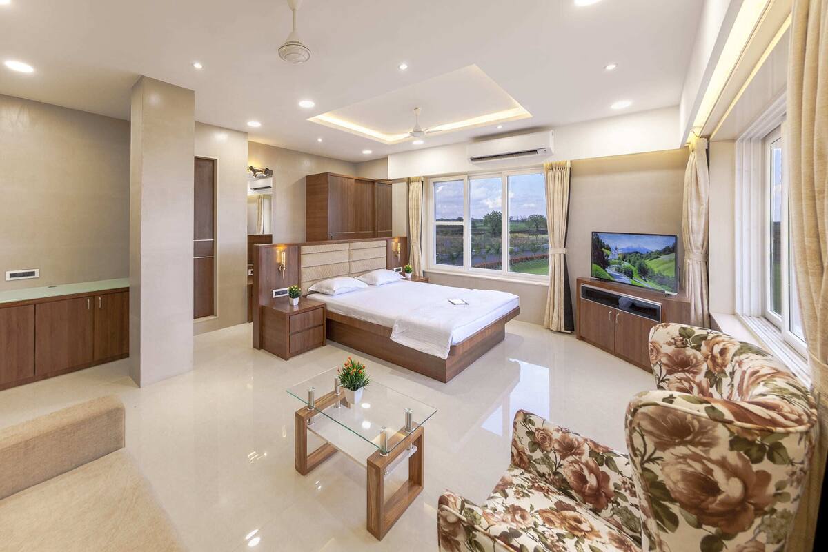A modern bedroom with a large bed, a TV, and a sofa.