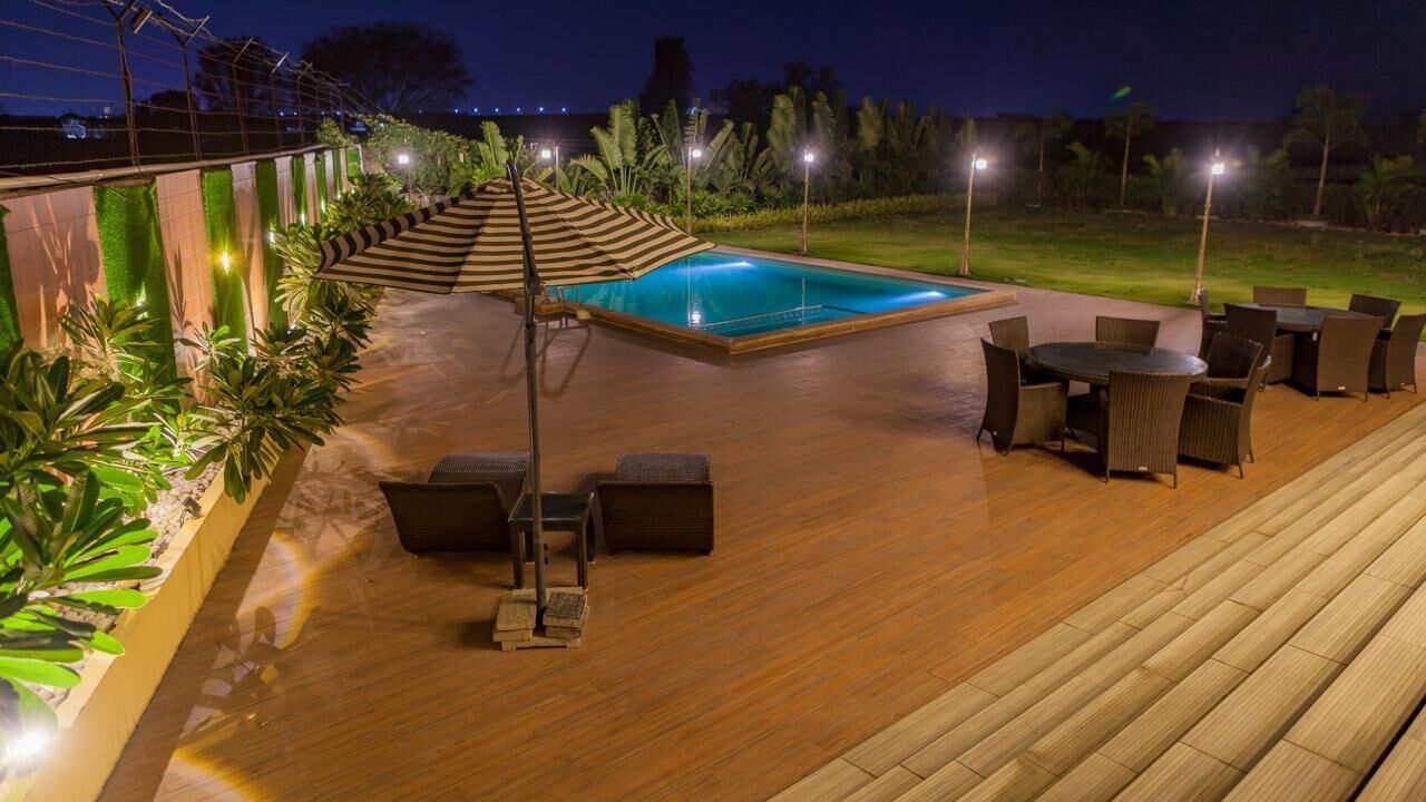An outdoor pool area with a wooden deck, lounge chairs, and a small table.