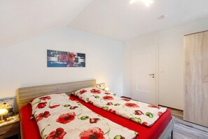 Une chambre à coucher avec un lit double, une table de chevet avec une lampe, une armoire en bois et un tableau accroché au mur.