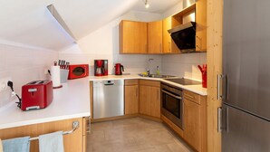 A modern kitchen with wooden cabinets, stainless steel appliances, and a white countertop. - Apartment 'Fewo Mit Balkon Am Wald 2-4 Pers' with Mountain View, Private Garden and Wi-Fi (Bad Sachsa)